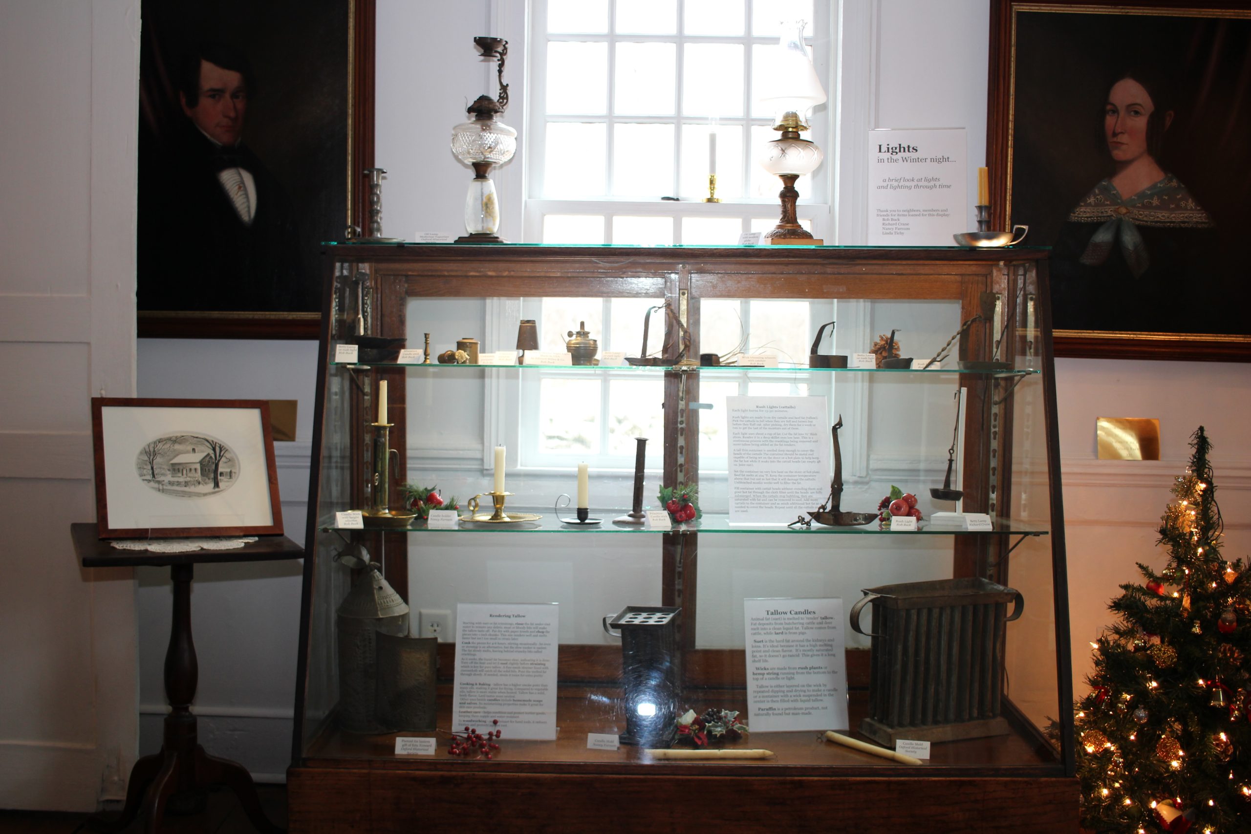A vintage display case from Oxford's Devaux store filled with lighting items of all ages. Portraits in rear are David Tomlinson and his wife of The Oxford House.
